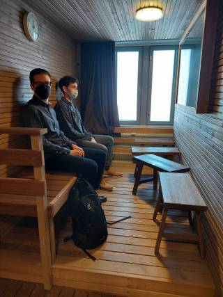 Kuvassa tila, joka sisustettu saunaksi ja lauteilla istuu kaksi hanketoimijaa.