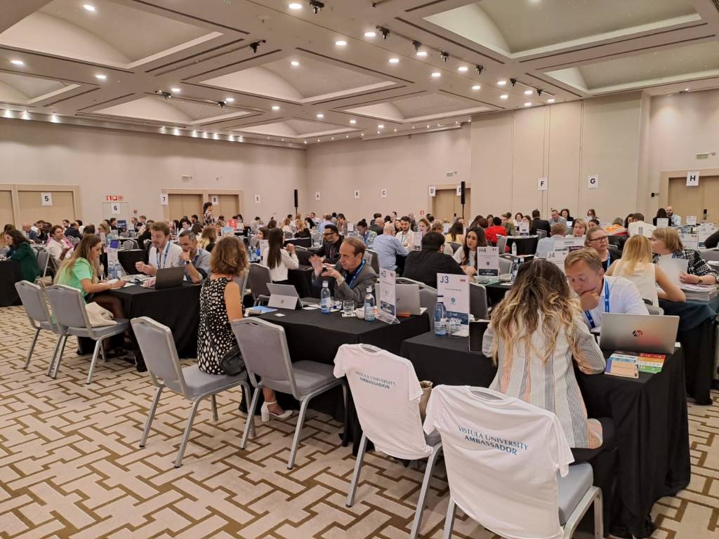 Big room where people are chatting in tables.