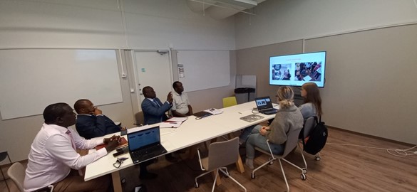 People sitting around the table and watching a screen.