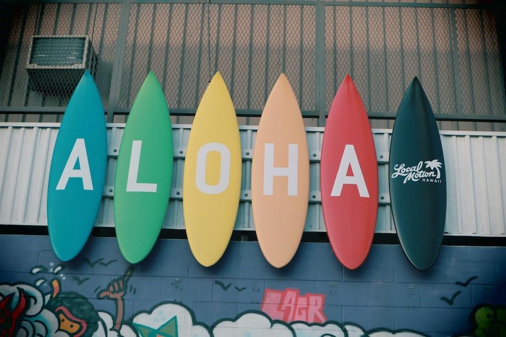 Six surf boards leaning against the wall with a text Aloha.