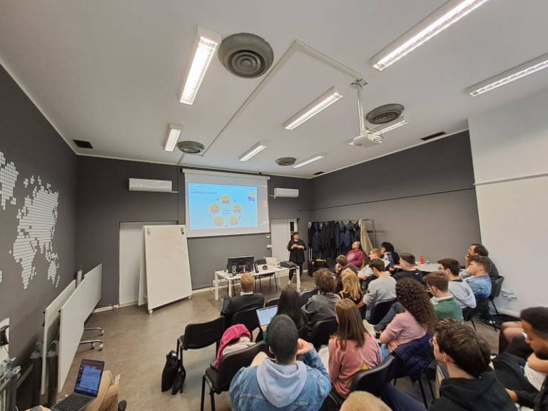 Students sitting in a classroom and watching a screen.