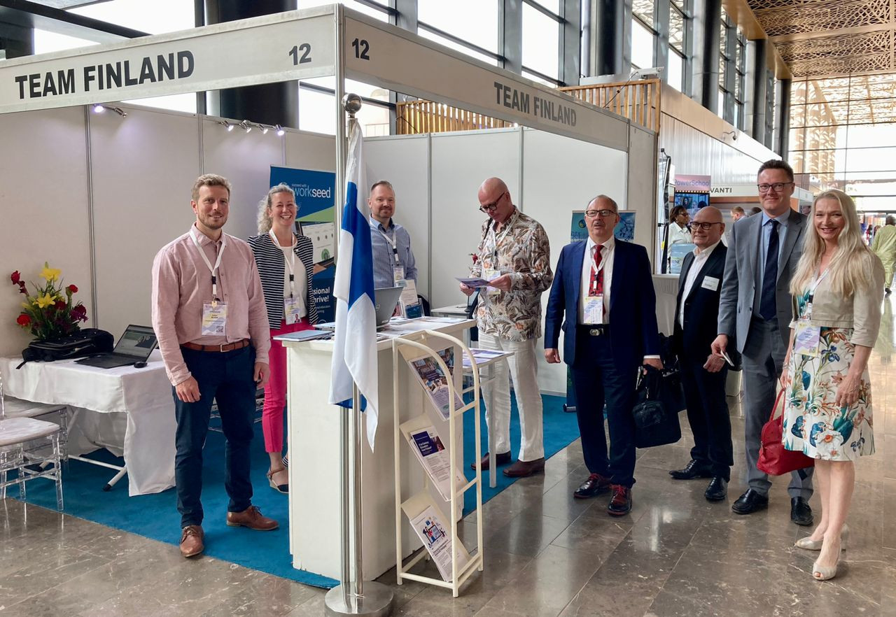 People standing and smiling at Team Finland exhibition booth.