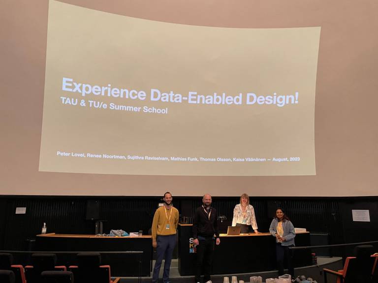 Four people in front of a screen with a text Experience Data-Enabled Design