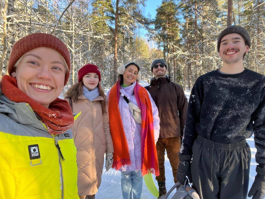 A group of friends taking a selfie in a winter forest and smiling.