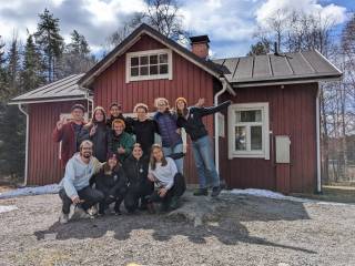 A group of students standing in front of a red cabin.