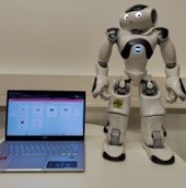 NAO robot next to a computer with the virtual classroom of the Elias robot app.