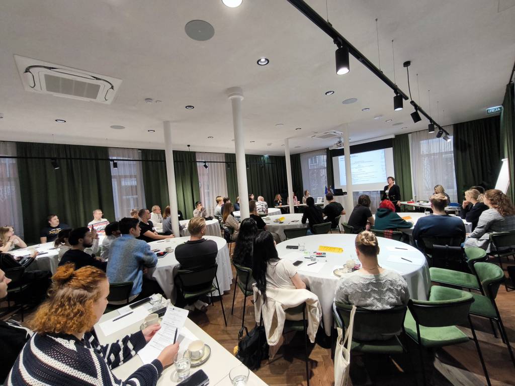 People sitting around tables and looking at a stage.