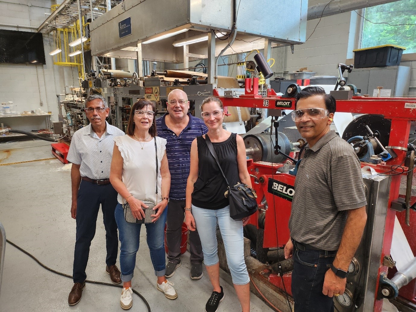 People standing in front of a paper machine.