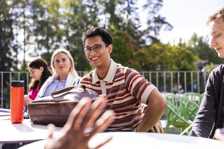 Students at Tampere University discussing their studies outdoors during summertime.